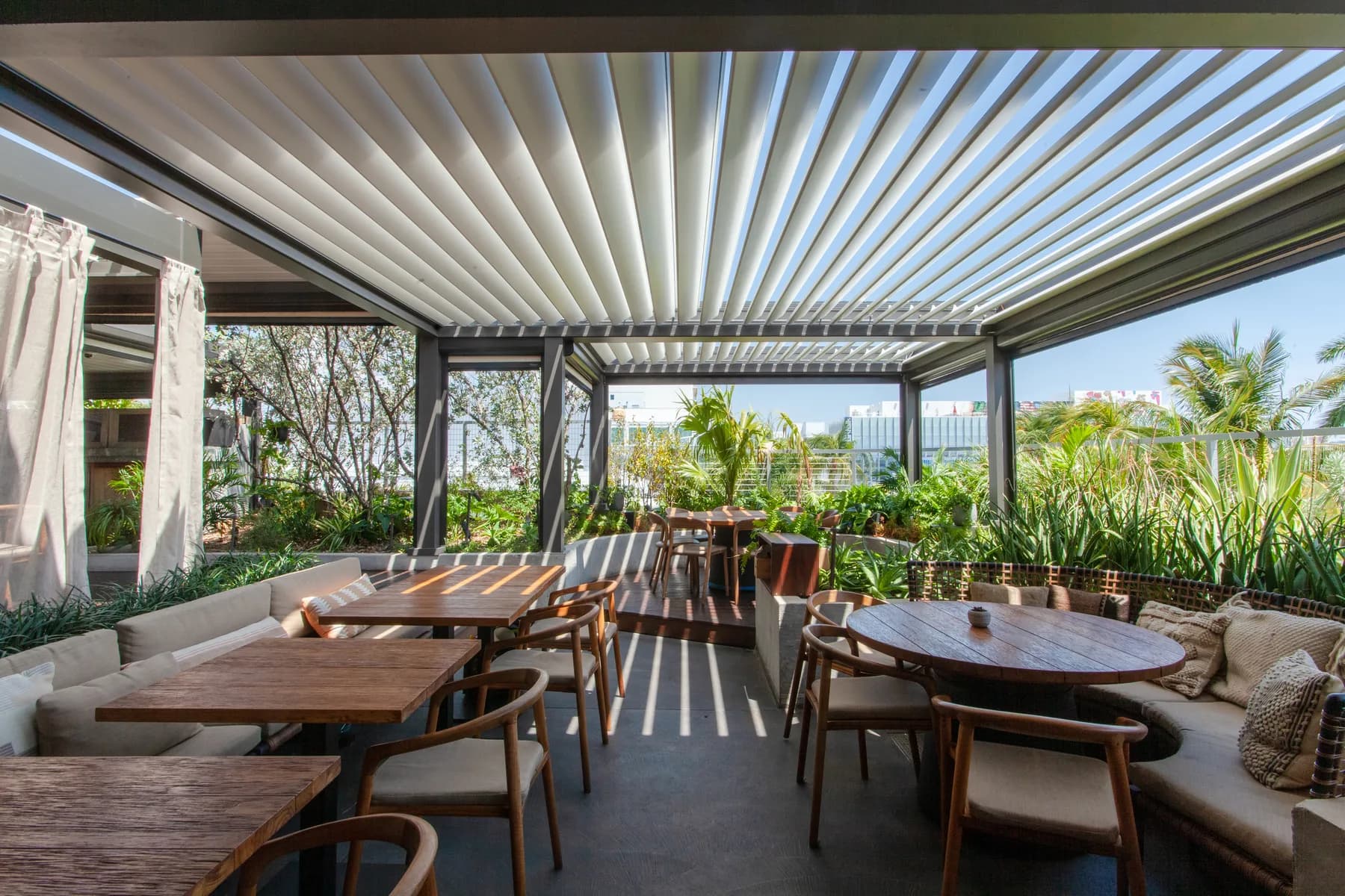 Azenco Outdoor louvered pergola with open louvers over an outdoor dining space