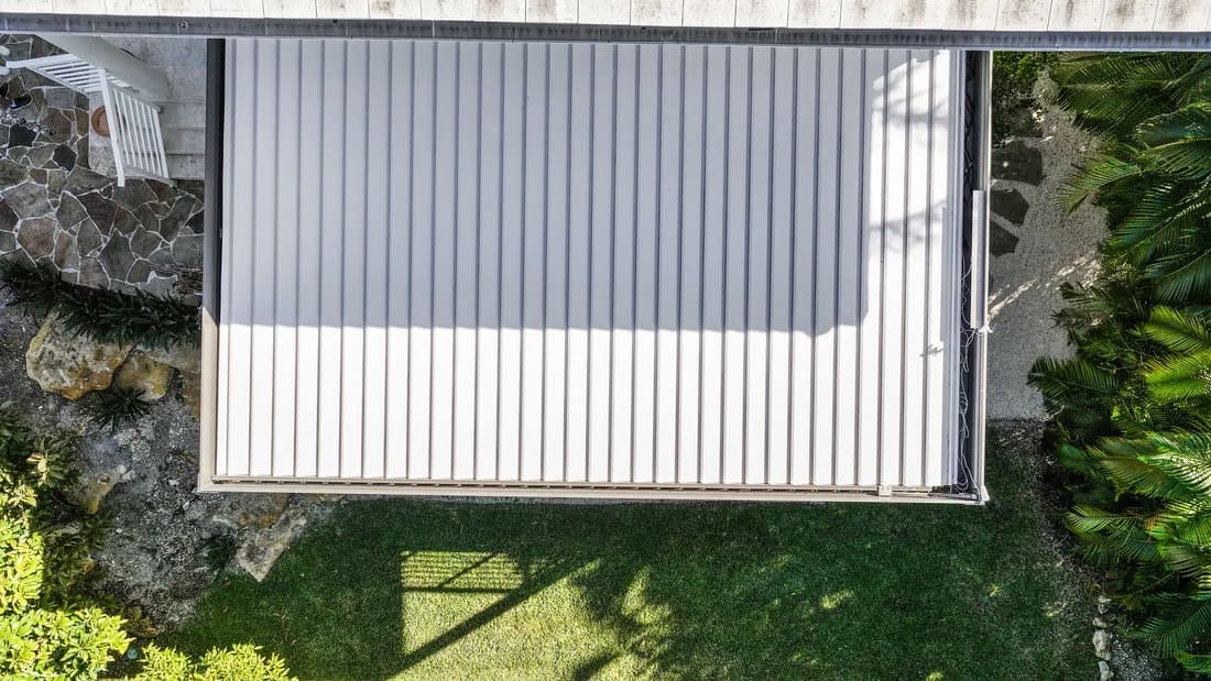 Aerial view of an Azenco Outdoor R-BLADE pergola roof closed against the home