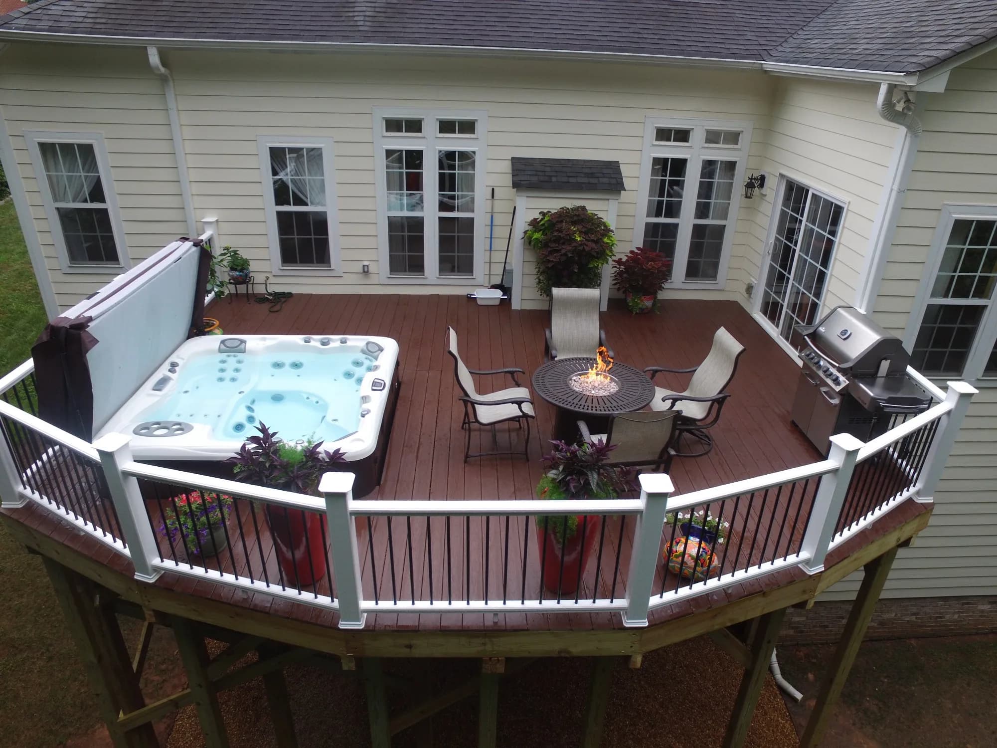 Elevated backyard deck with a built-in hot tub, fire-pit table, and grill in Charlotte, NC