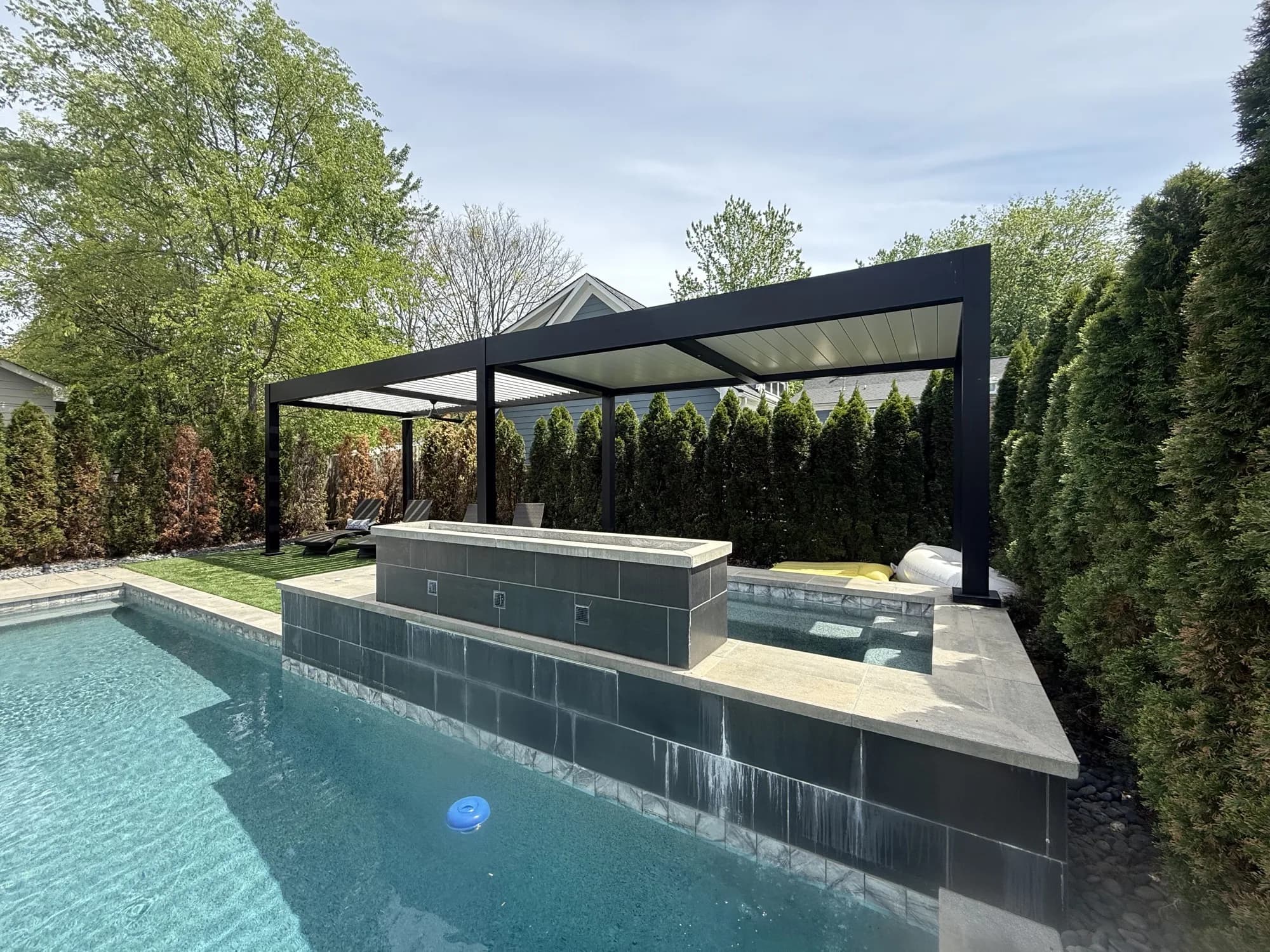 Modern louvered pergola over a spa beside an in-ground pool in Charlotte, NC