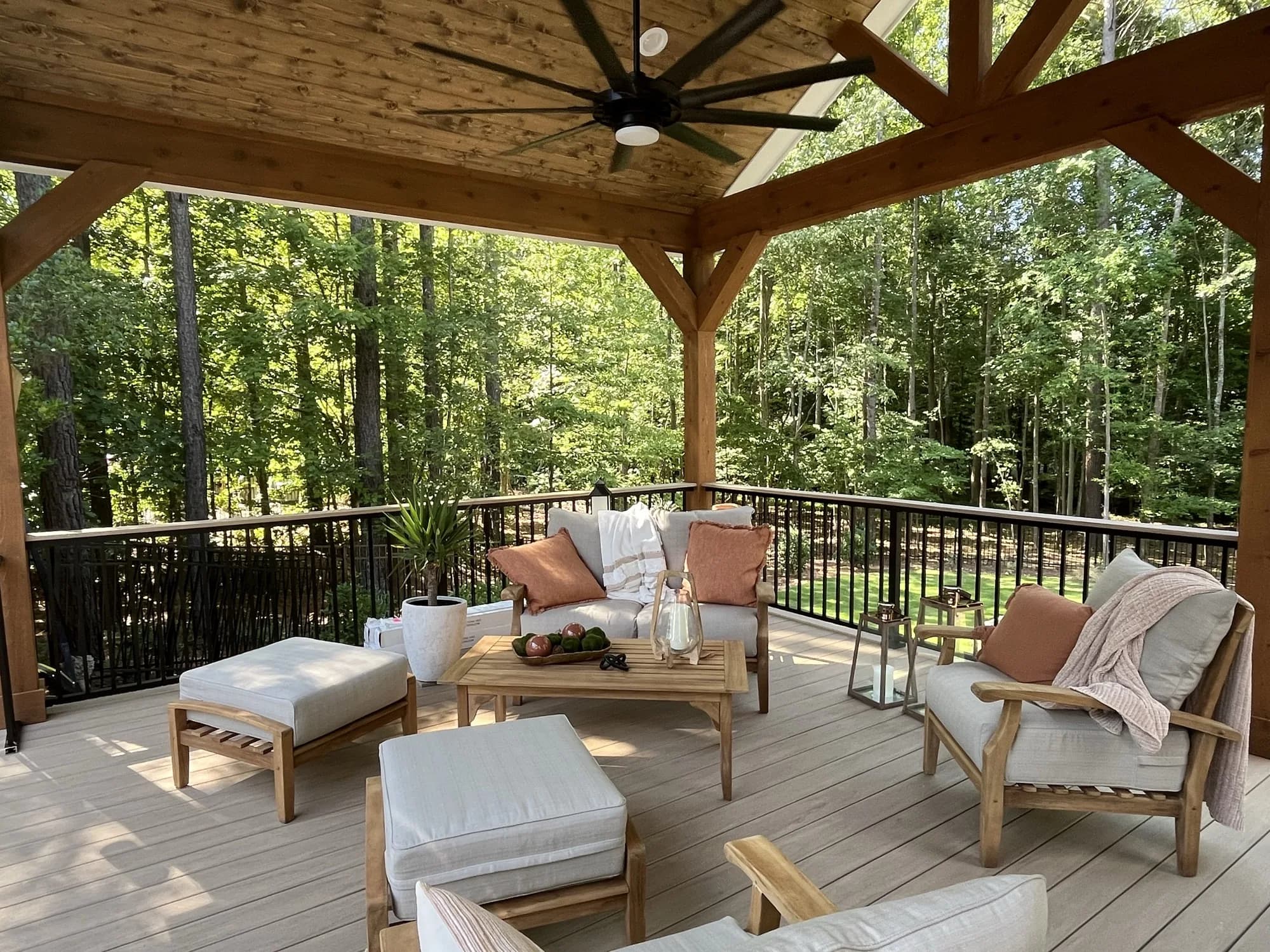 Covered outdoor living porch with a timber-frame ceiling and lounge seating overlooking the woods in Charlotte, NC